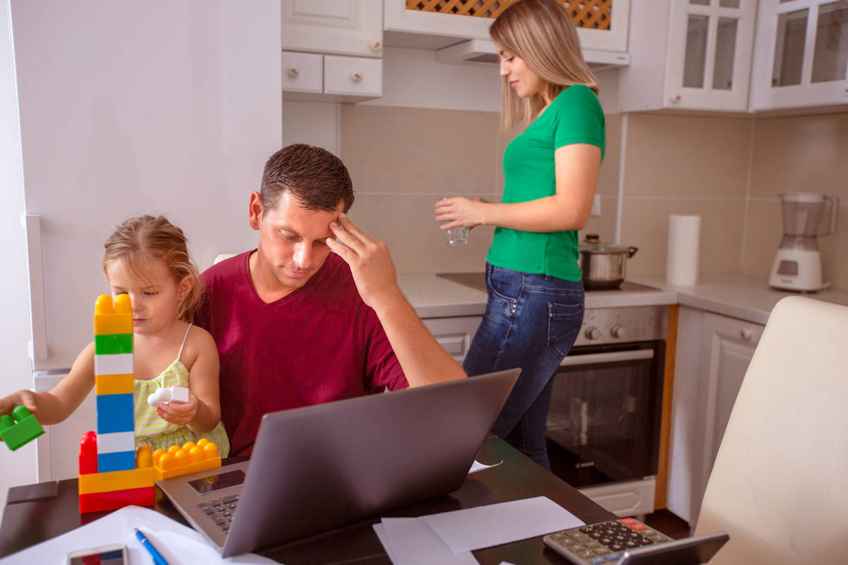 Busy family - busy man working with computer while looking after his daughter.